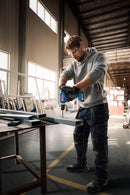 Man using a Bosch drill in a workshop setting to drill metal